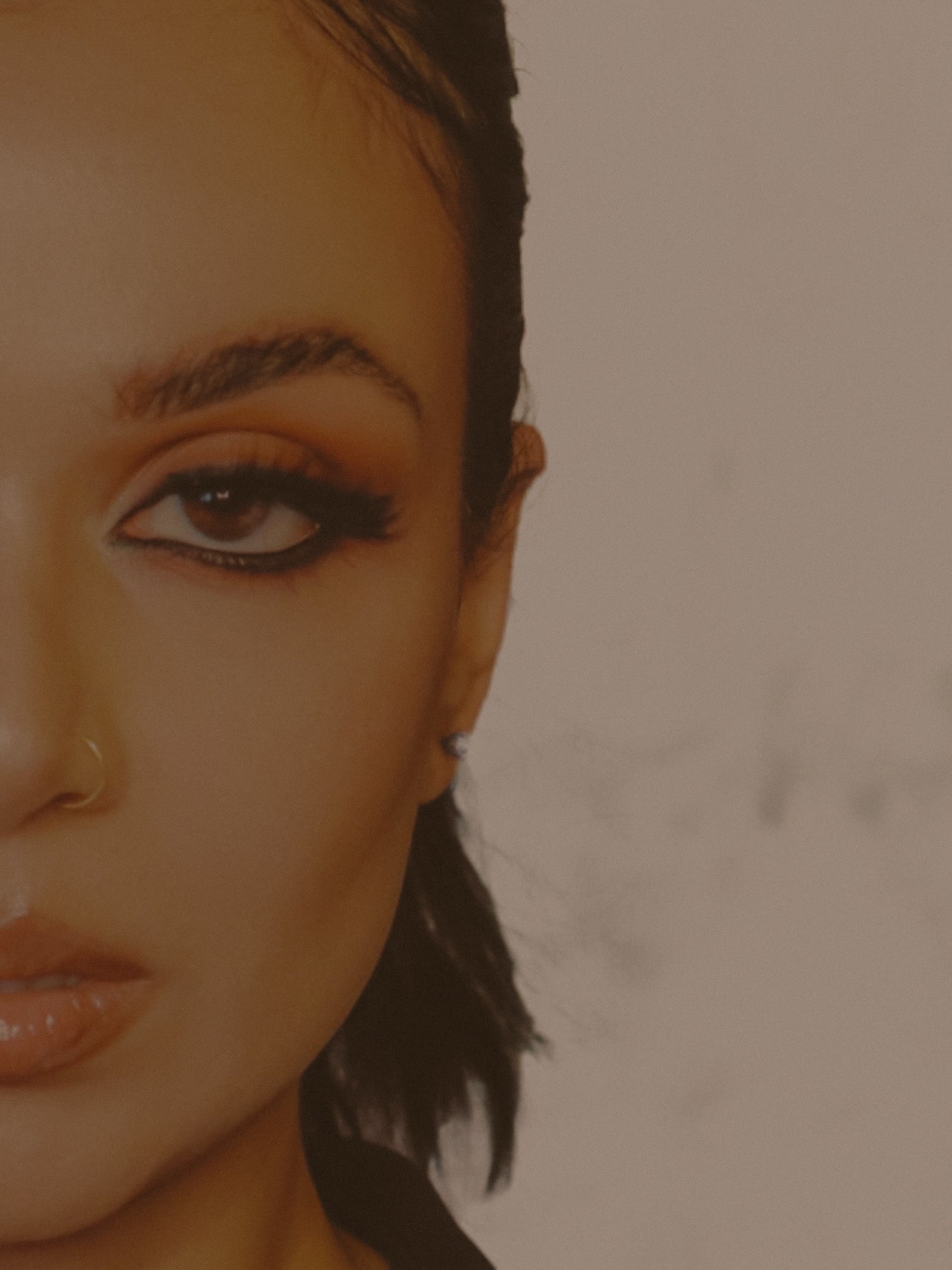 Close-up of a woman’s face wearing dramatic sultry lashes, softly lit with a nostalgic, filmic tone. A dreamy, editorial portrait for Suntarah's Signature Edit false lash collection.